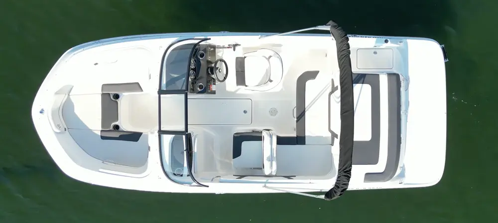 Top view of a white boat on water with seating and control area.