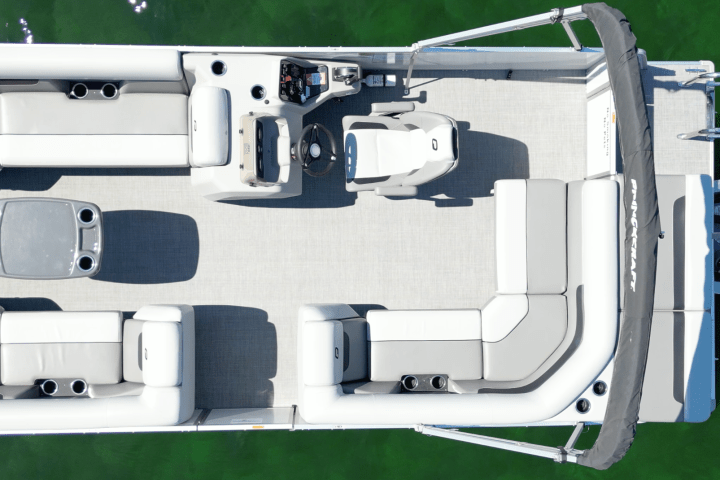 Top-down view of an empty pontoon boat on green water.