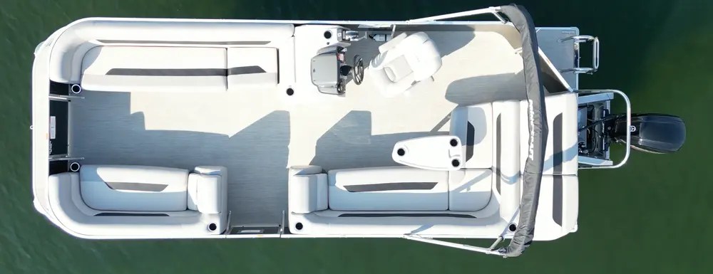 Top view of a motorboat with seating and steering console on water.
