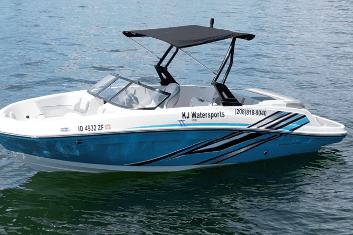 Small blue and white speedboat with a black canopy on the water.