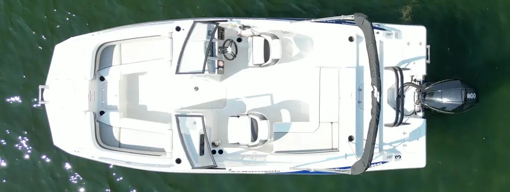 Aerial view of a white motorboat on water, showing seats and steering wheel.