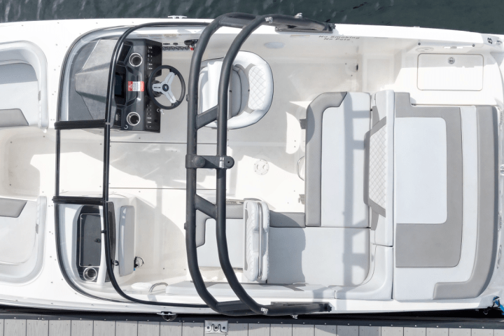 Top view of a white motorboat docked, showing seats, steering wheel, and outboard motor.