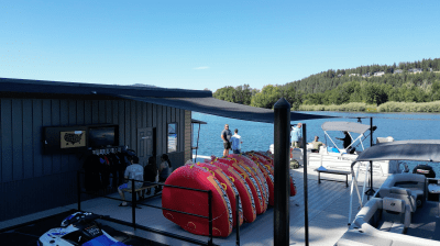Boat dock with stacked red rafts and people by the water.